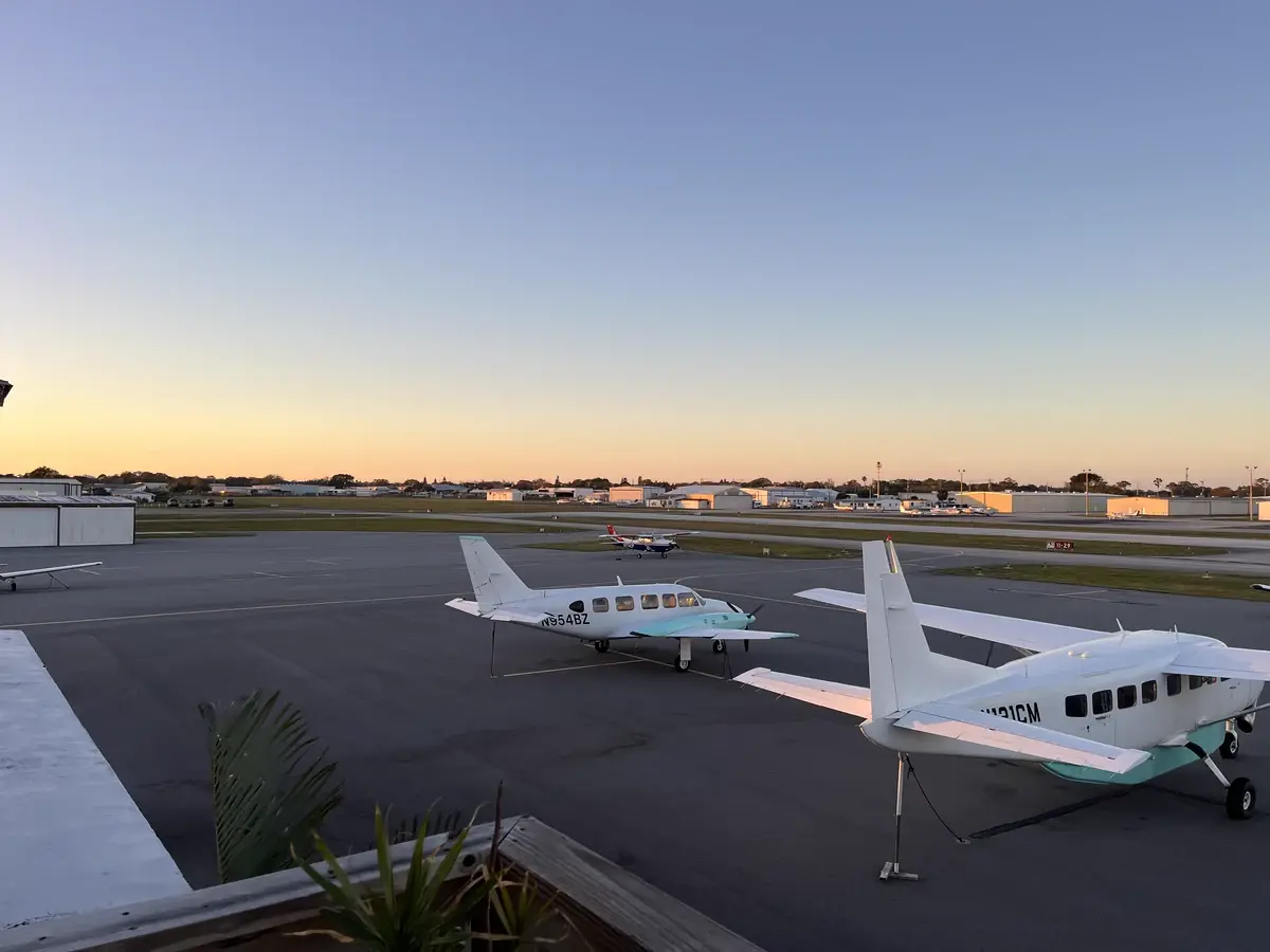 General aviation aircraft cruising over scattered clouds at sunset